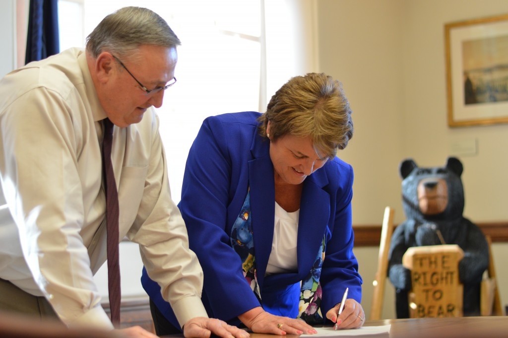Sen. Susan Deschambault, right, signs paperwork to certify her swearing-in as the the newest member of the Maine Senate after being sworn in by Gov. Paul LePage on Tuesday, April 5.